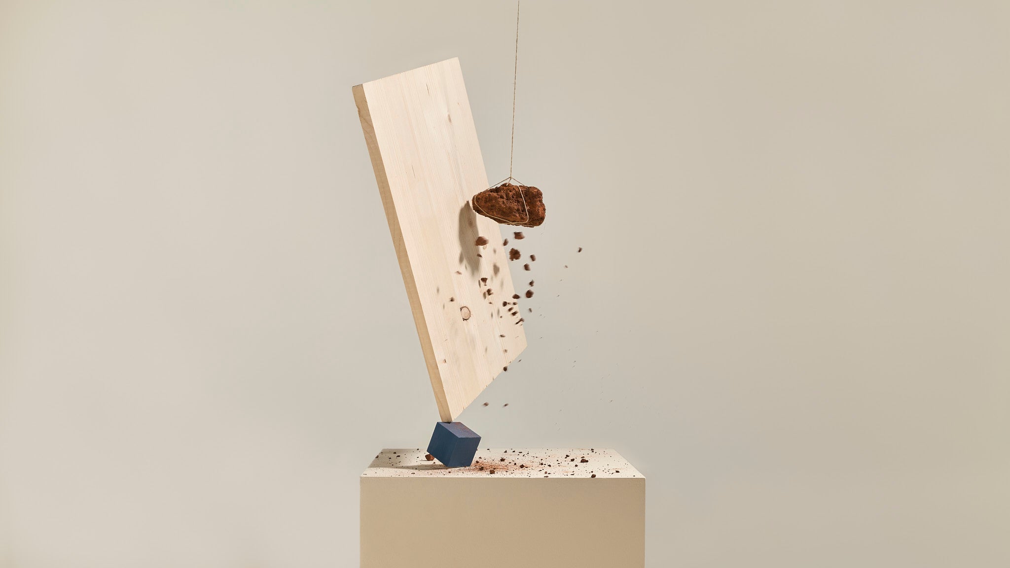 Planche en bois massif flottant dans les airs, percutée par une pierre qui se brise, symbole de robustesse naturelle