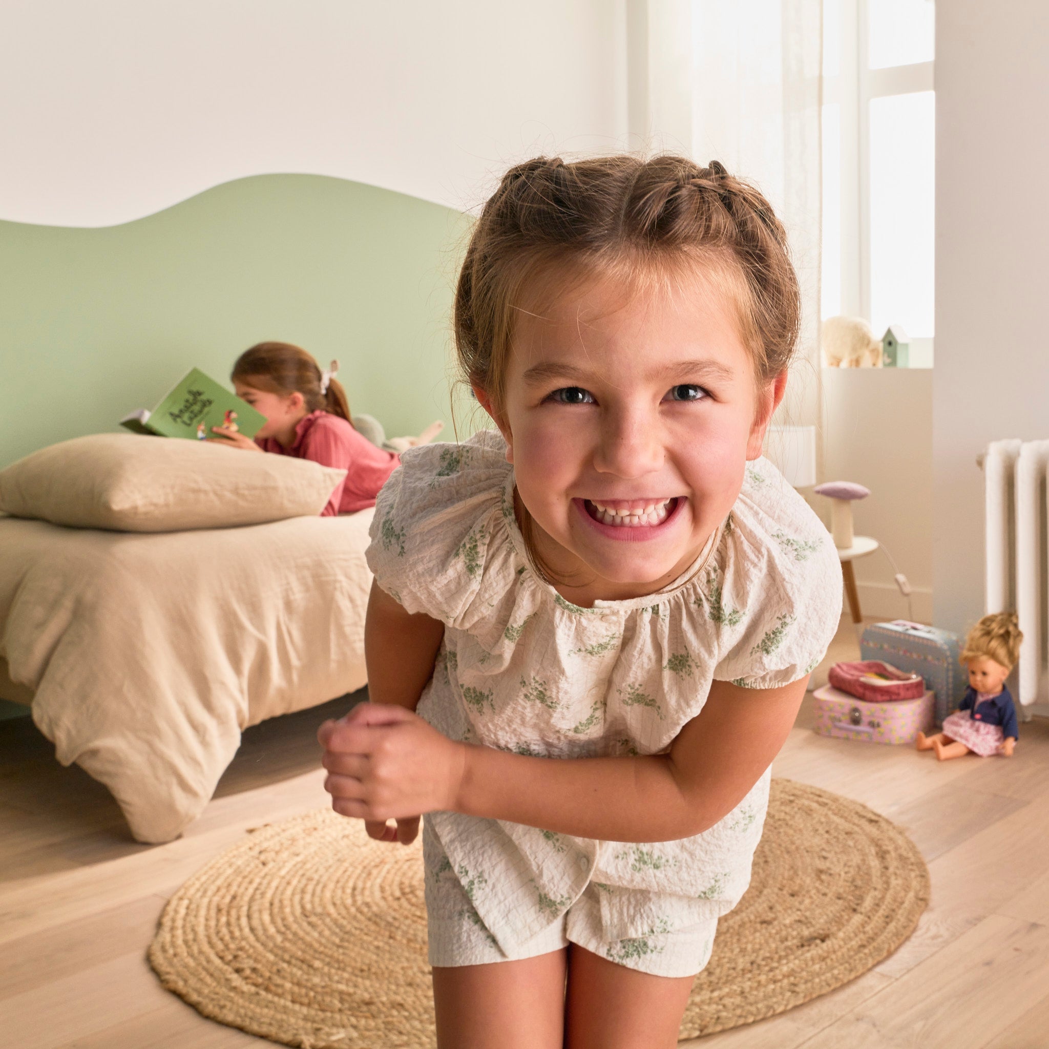 Petite fille très souriante en gros plan, devant une chambre d’enfant Bonnuit, illustrant la sincérité et la confiance au cœur de la marque