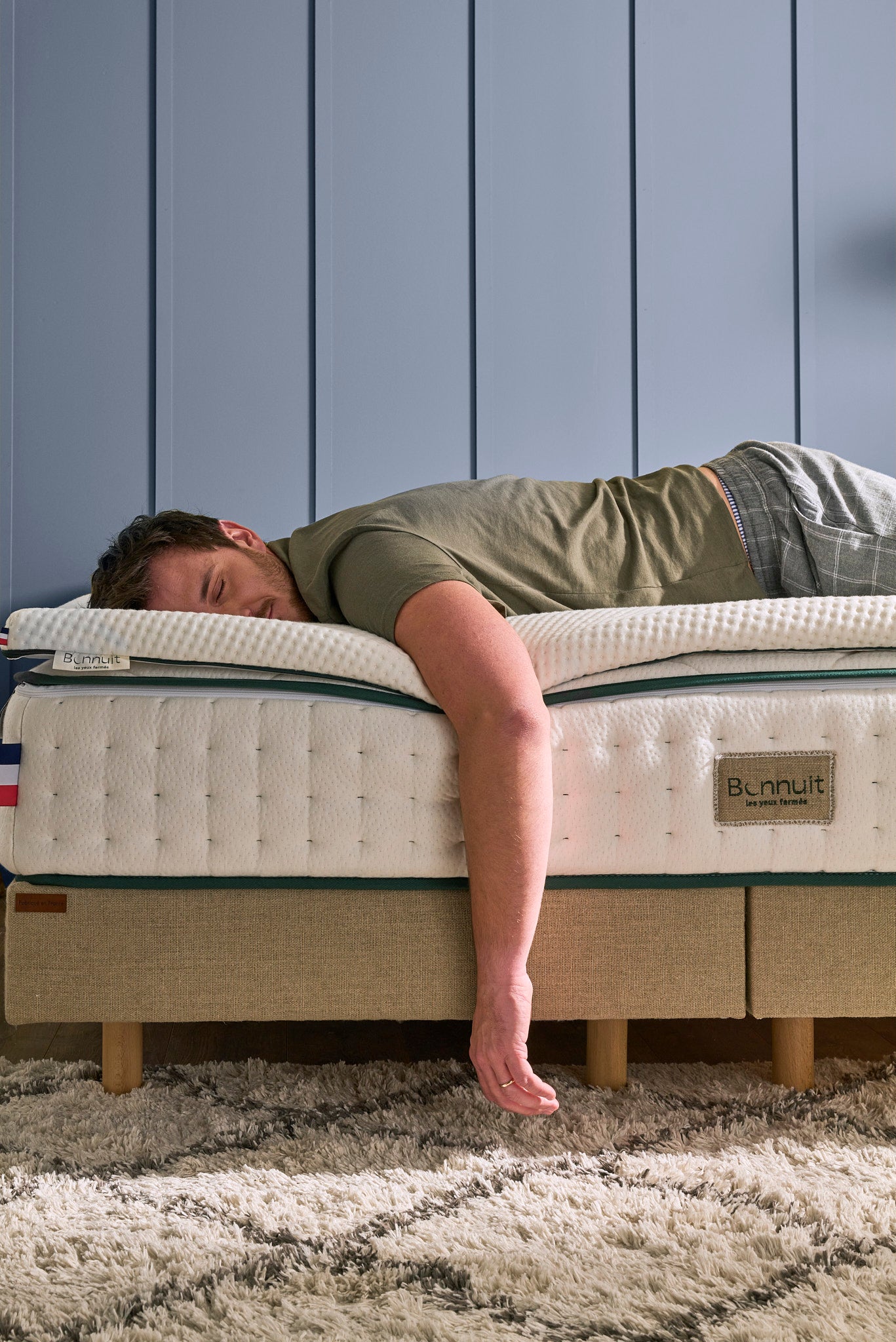 Homme allongé sur le ventre au bout d’un lit Bonnuit, un bras relâché dans le vide, illustrant une sensation de confort total
