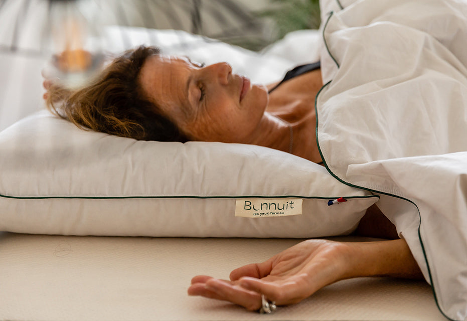 Femme reposée allongée sur un oreiller Bonnuit, avec l’étiquette Bonnuit et la finition bleu blanc rouge bien visibles