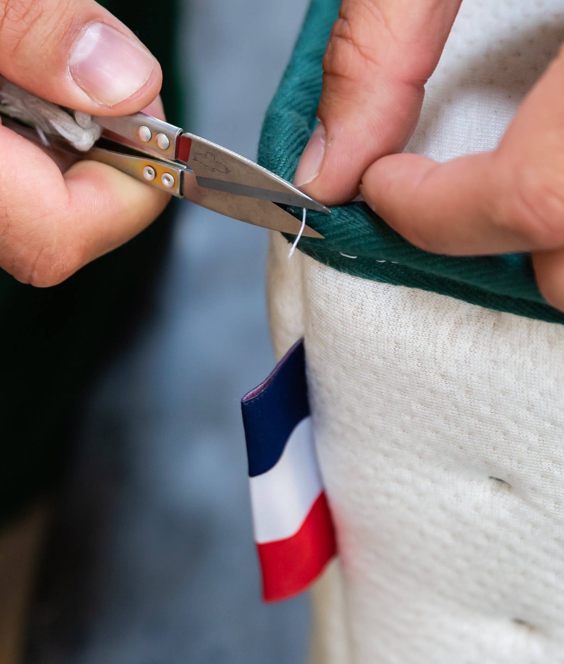 Zoom sur une housse de matelas Bonnuit avec couturière réalisant la finition, drapeau français visible en détail