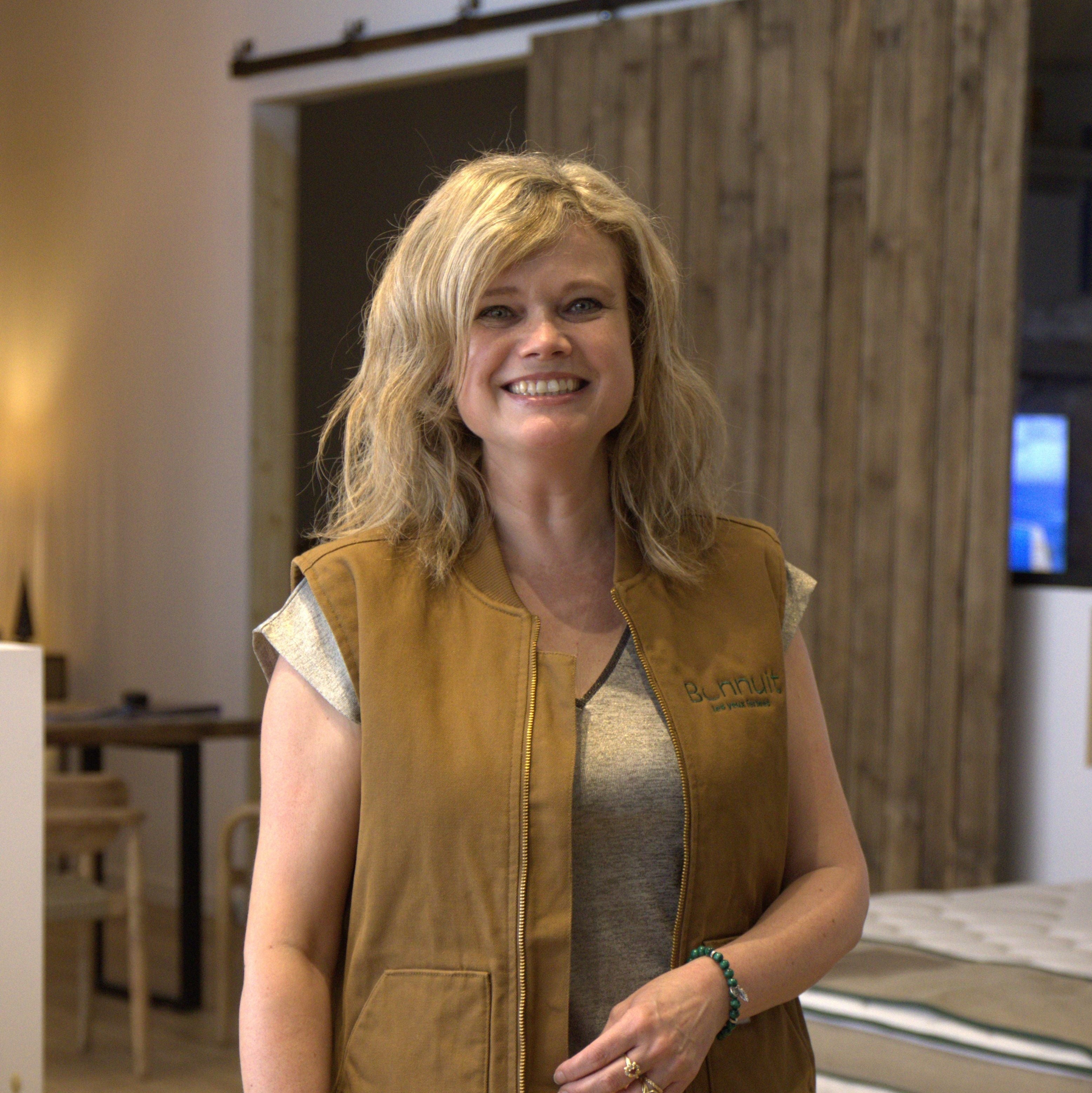 Portrait de la vendeuse du magasin de literie Bonnuit à Cysoing, souriante et vêtue d’une veste marron Bonnuit
