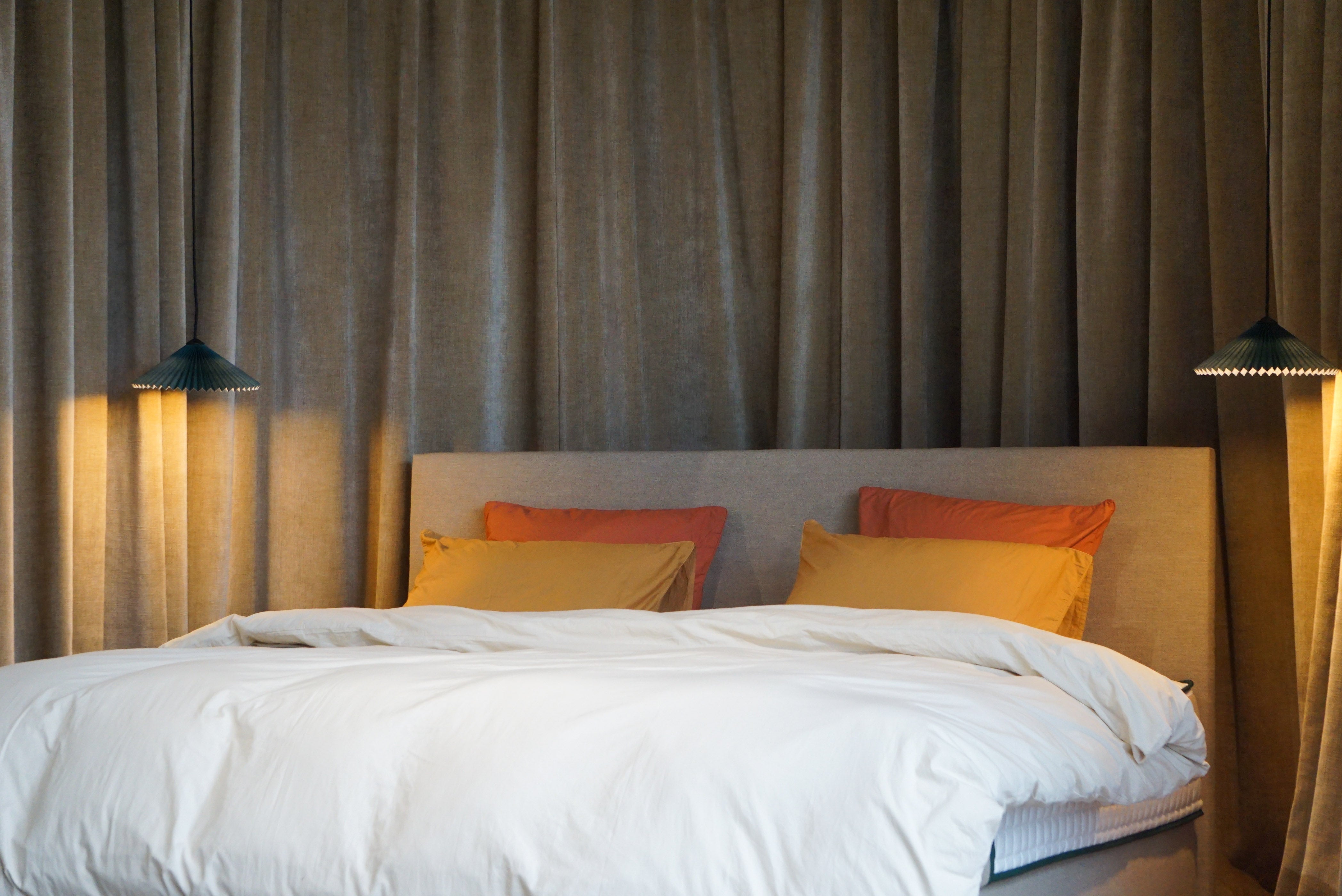 Matelas Bonnuit avec sa tête de lit en lin ainsi qu'une parure en percale lavée dans les tons ocre.