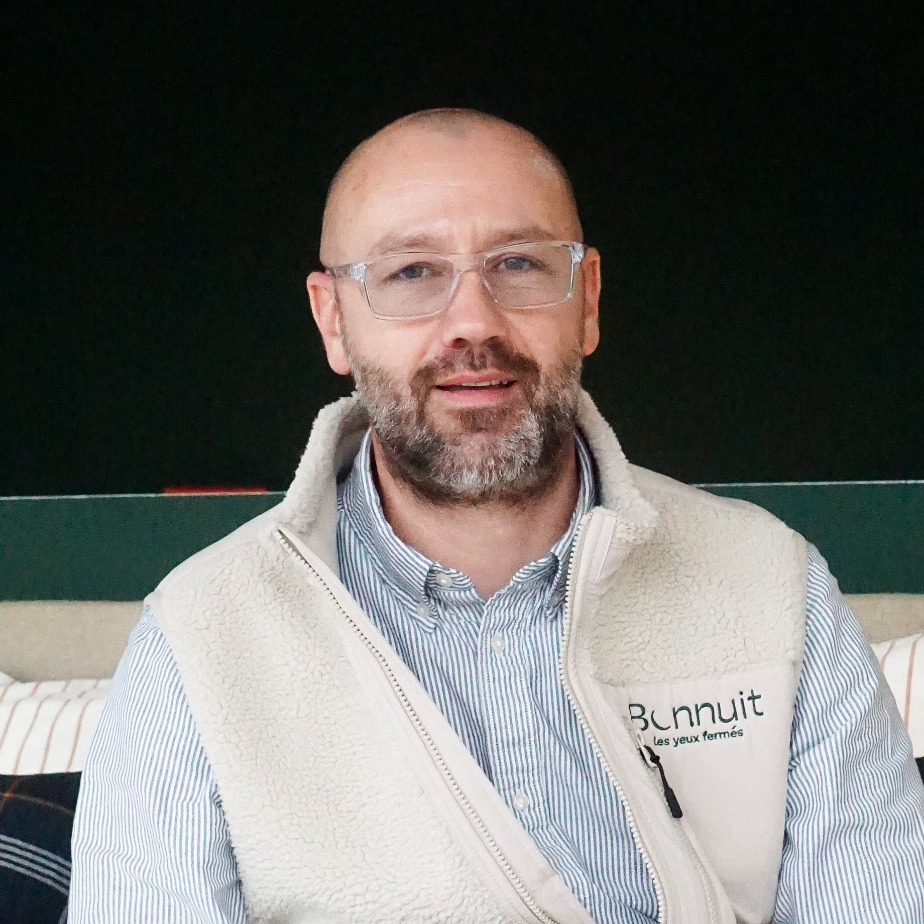 Portrait du vendeur du magasin Bonnuit à Douai, souriant avec une veste Bonnuit blanche