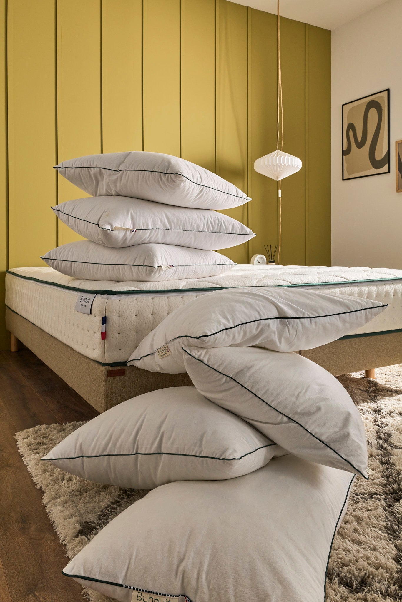 Pile d’oreillers Bonnuit exposés sur un lit — lien vers la page Nos accessoires
