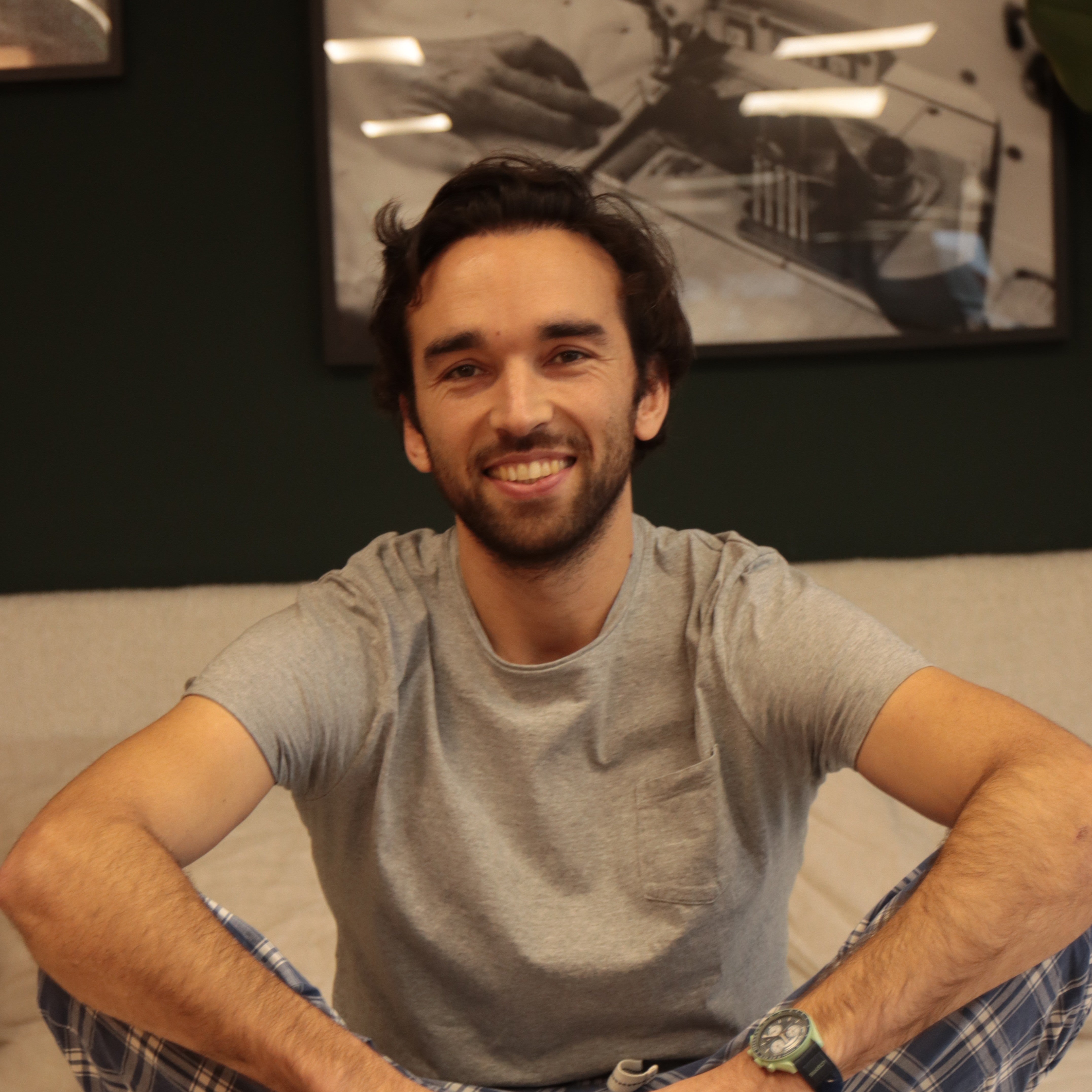 Cédric, co-fondateur de Bonnuit, assis en pyjama sur un lit de la marque, incarnant simplicité et esprit maison