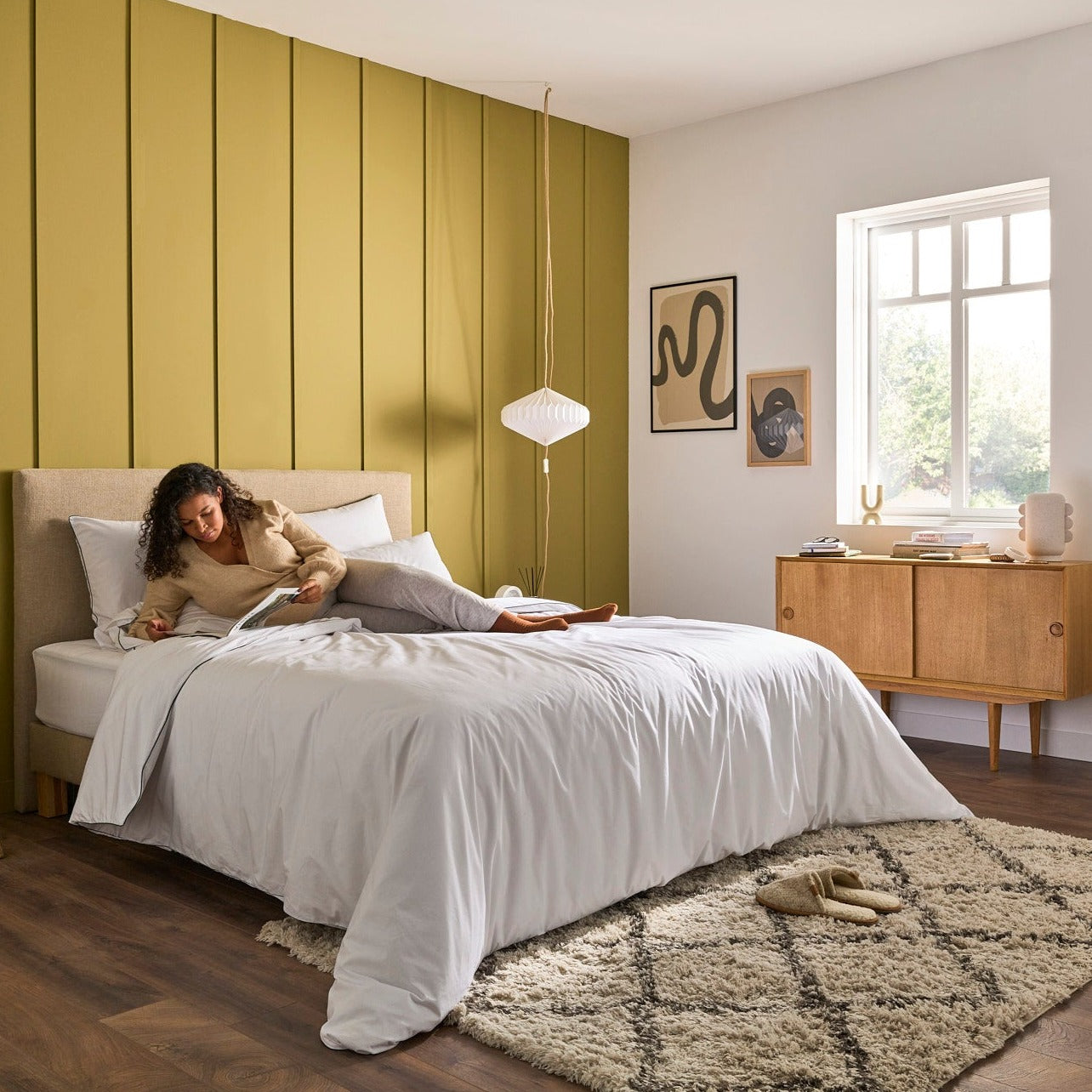 Femme lisant sur une literie Bonnuit avec la couette Polyvalente, linge de lit blanc en percale à liseré vert