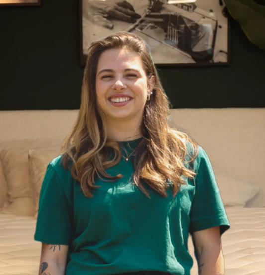 Emma, chargée de l’administration des ventes chez Bonnuit, assise sur un lit avec un sourire chaleureux