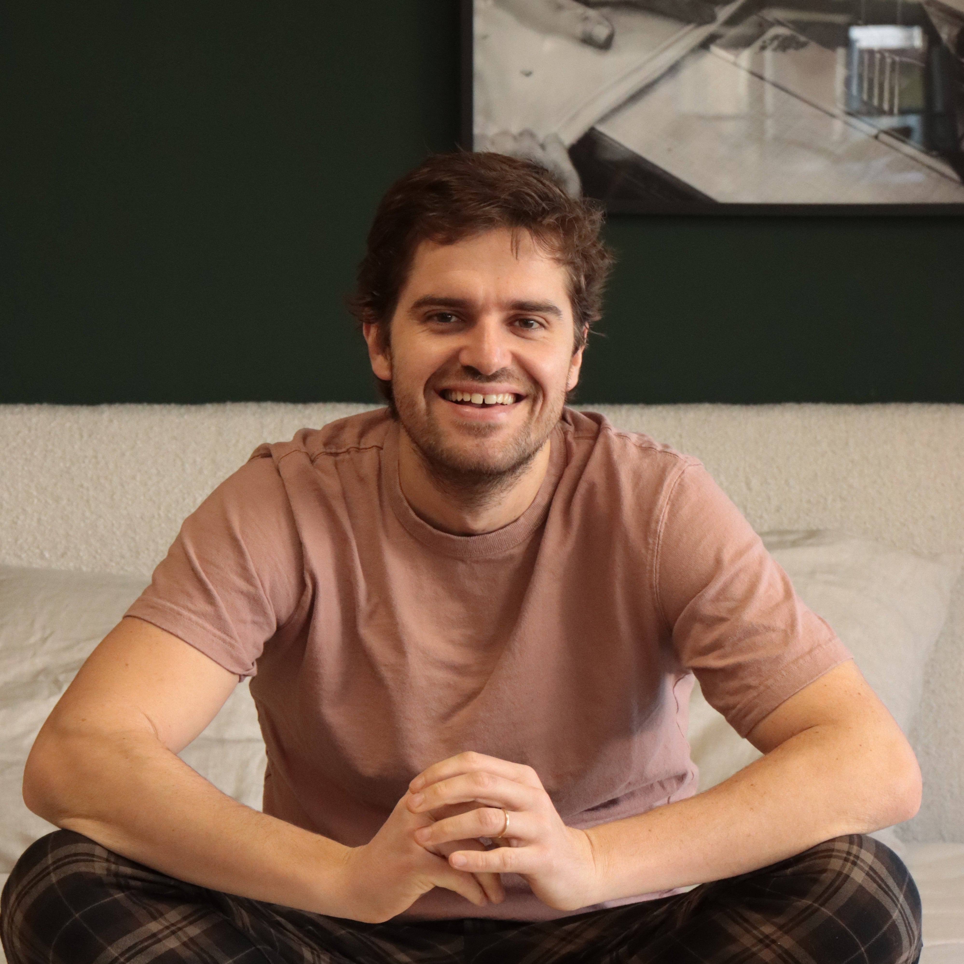 Félix, co-fondateur de Bonnuit, assis en pyjama sur un lit de la marque, regard complice et posture décontractée