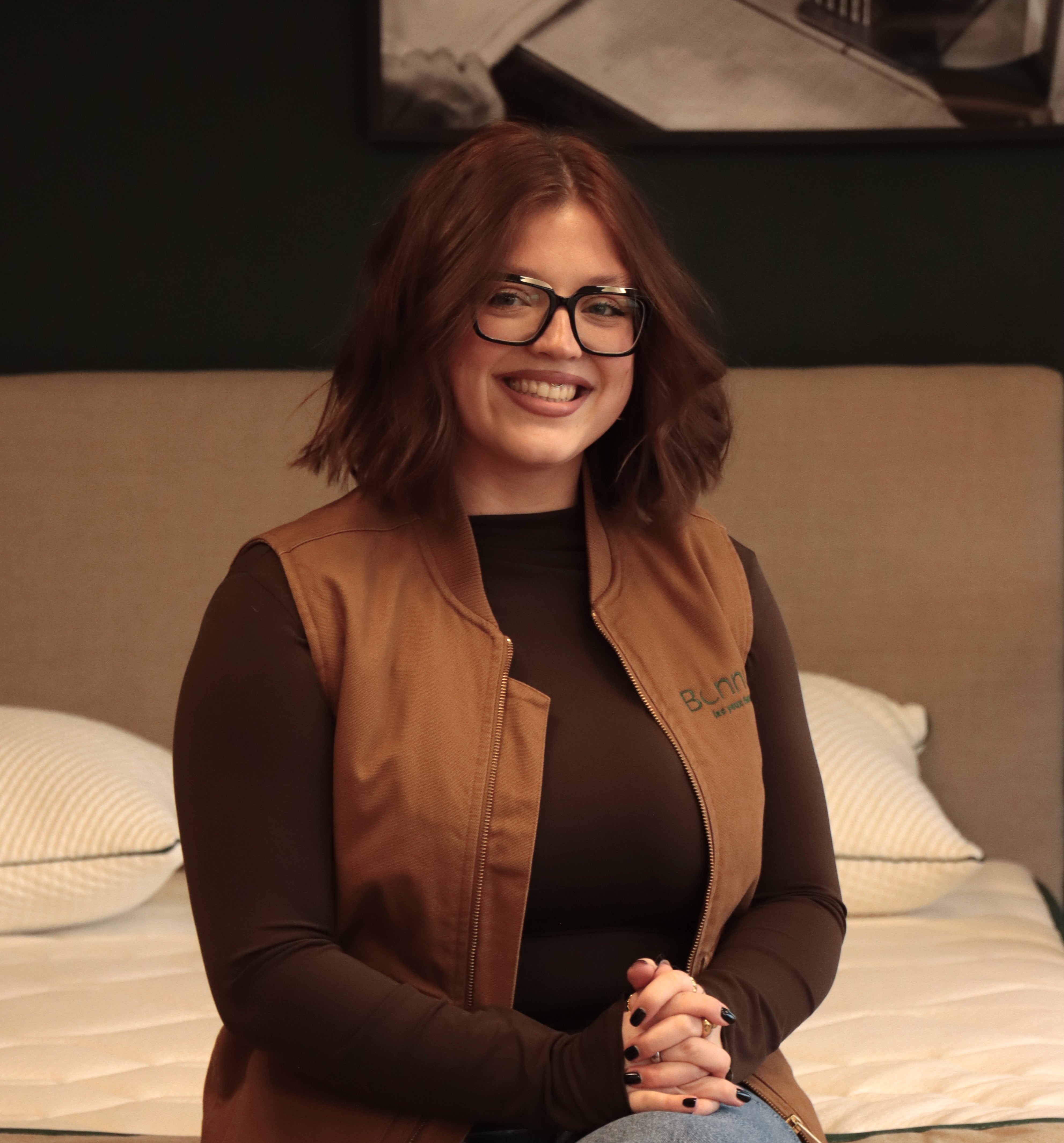 Jeanne, commerciale Bonnuit, assise sur un lit avec un sourire lumineux et une attitude chaleureuse