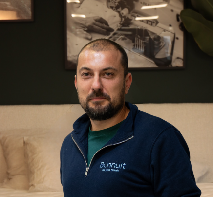 Julien, coupeur Bonnuit, assis sur un lit de la marque, expression détendue et naturelle