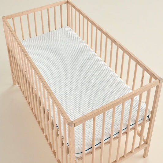 Matelas bébé Évolutif vu en angle, housse bicolore et liseré vert, format lit à barreaux