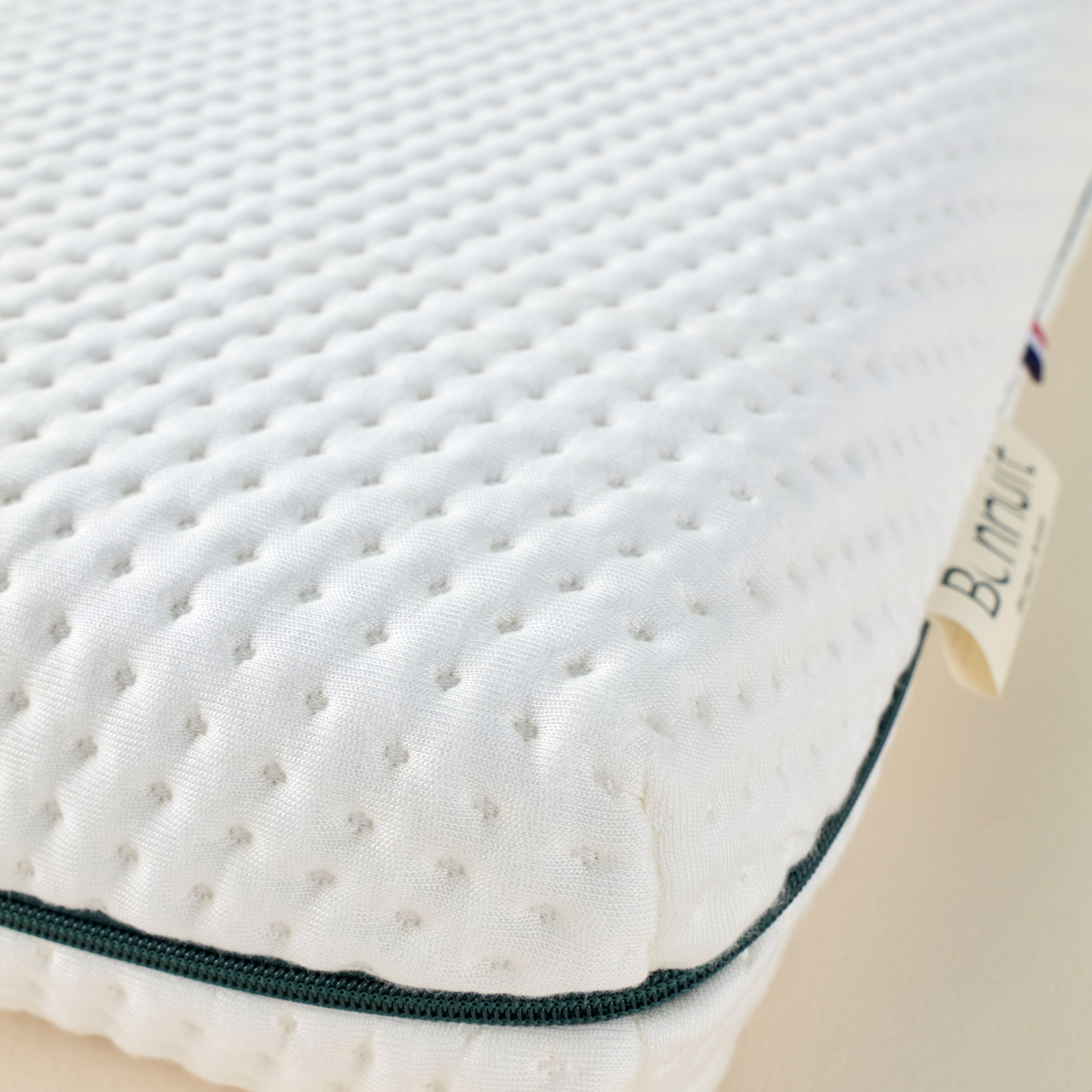 Zoom sur le coin du matelas Mini Mousse avec étiquette Bonnuit brodée et liseré bleu