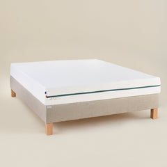 Matelas L’Essentiel Bonnuit en latex naturel et mousse, vue 3/4 avec housse blanche et fermeture verte, logo brodé sur lin