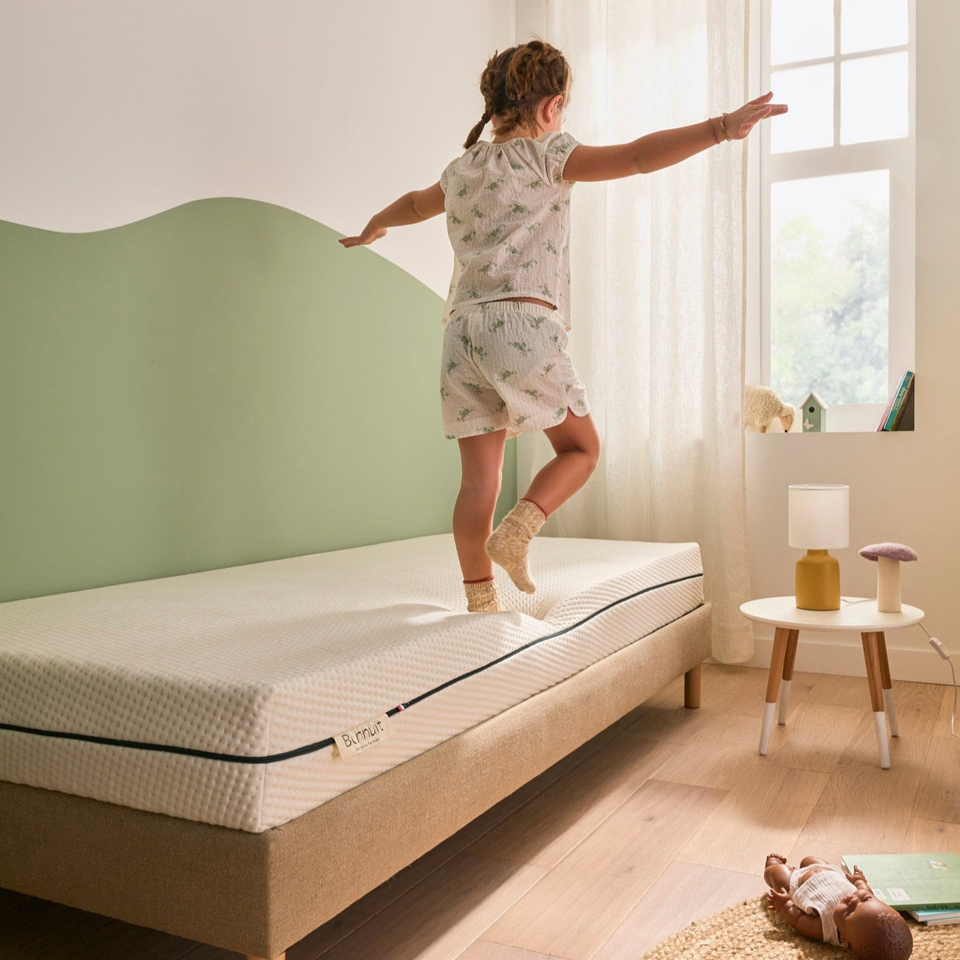 Petite fille debout sur le bord du lit Bonnuit L’Essentiel