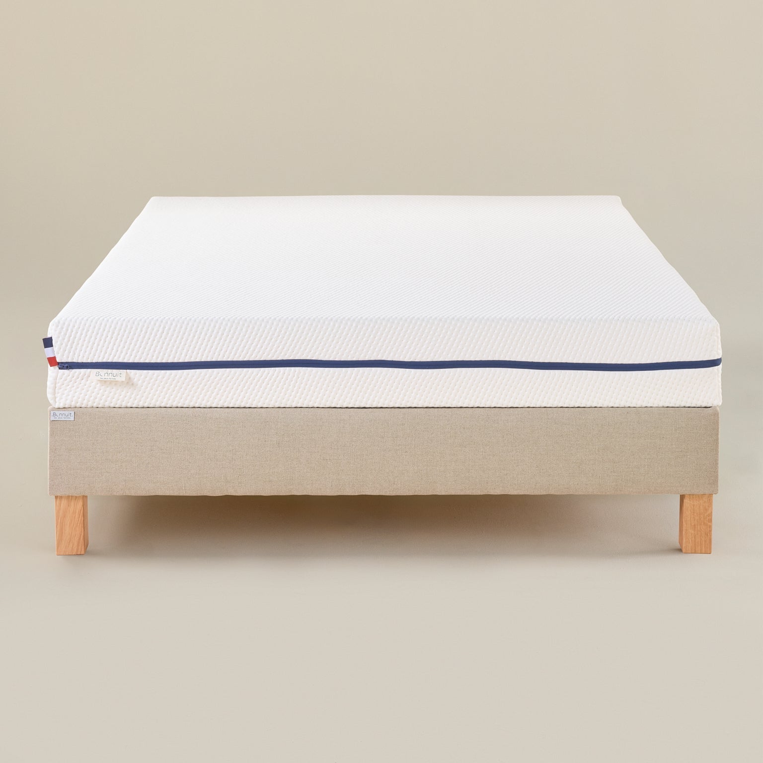 Matelas Le Pratique vu de face, housse claire avec liseré bleu et logo discret sur le tissu