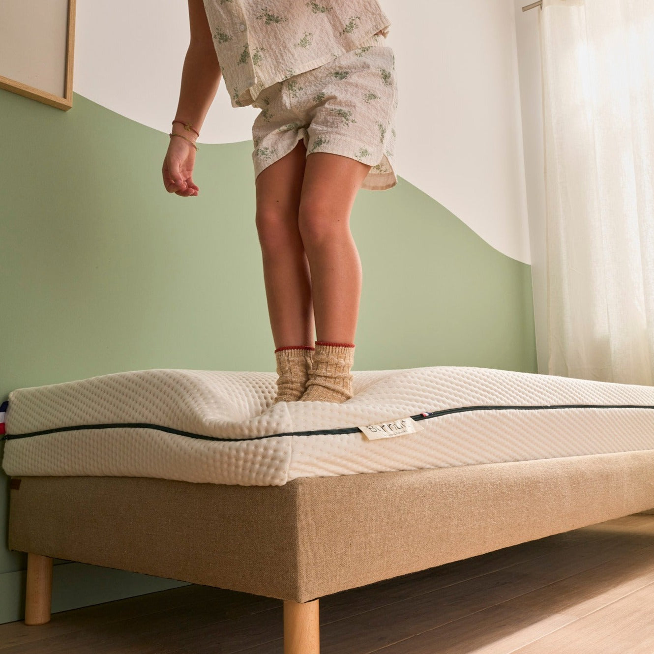 Enfant debout sur le matelas Le P’tit Mousse en train de jouer, zoom sur l’étiquette Bonnuit et drapeau bleu blanc rouge