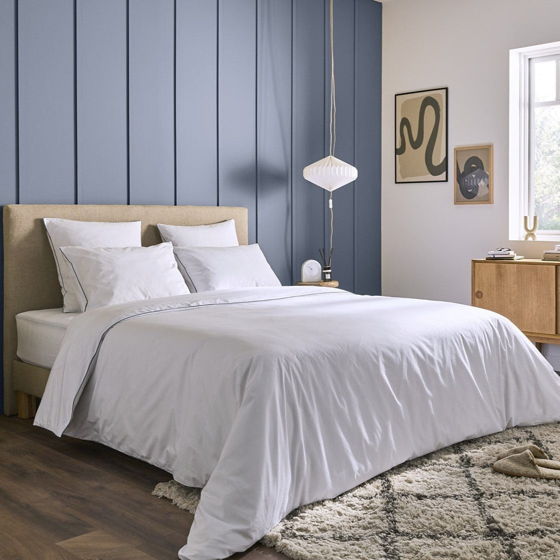 Matelas Le Majestueux Bonnuit habillé d’une parure blanche, dans une chambre sobre et élégante