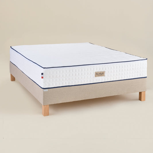 Matelas Le Majestueux Bonnuit en ressorts ensachés et mousse à mémoire de forme, vue 3/4 avec liseret bleu et logo brodé sur lin