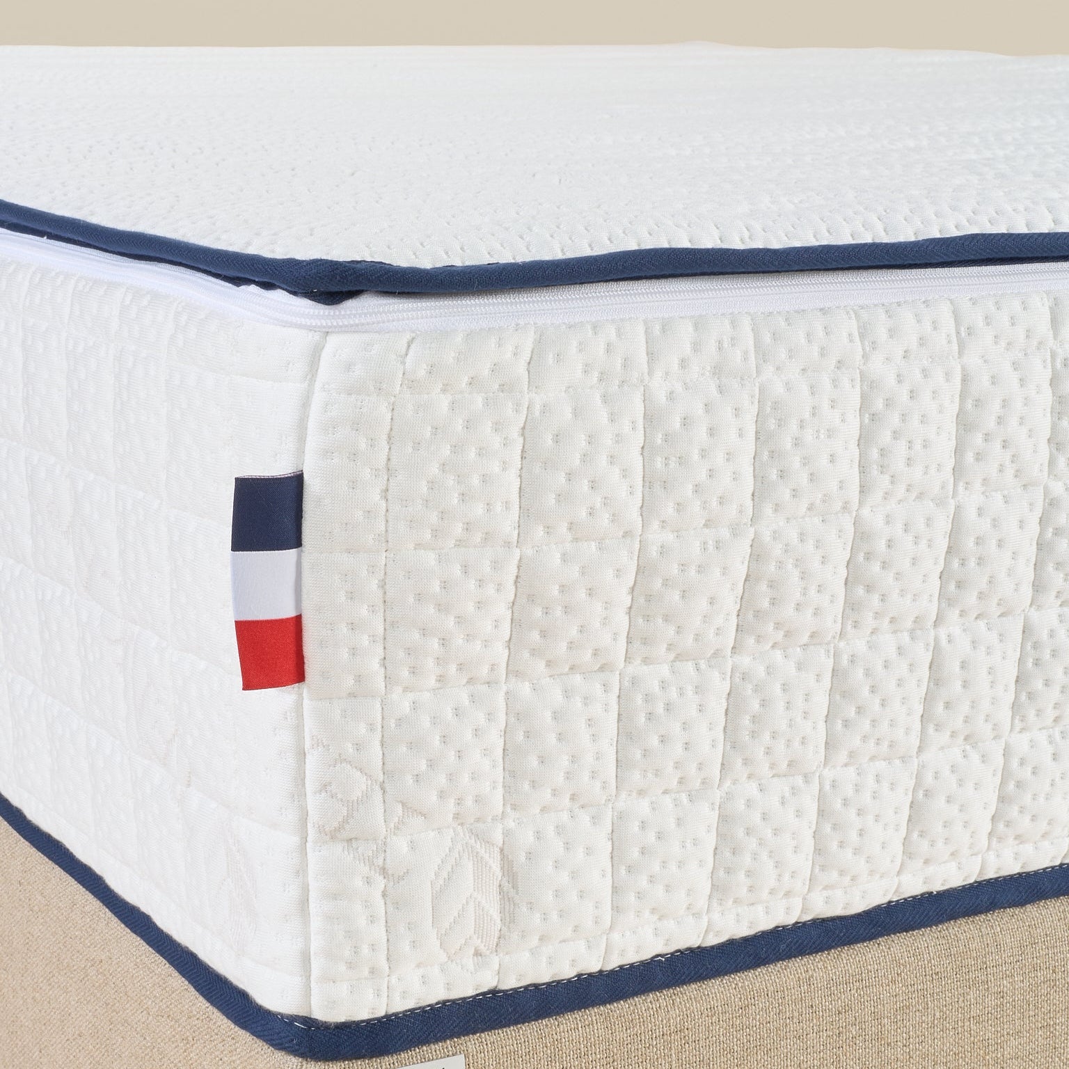 Zoom sur le coin du matelas Le Majestueux Bonnuit avec liseret bleu, logo brodé sur lin et drapeau français