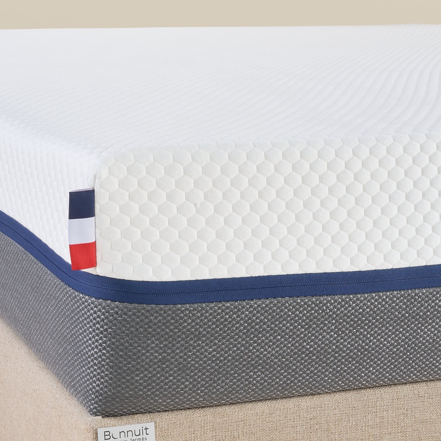 Zoom sur le coin du matelas Le Nuage Bonnuit avec housse bicolore, logo brodé sur lin et drapeau français