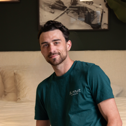 Mathis, matelassier Bonnuit, assis sur un lit de la marque, regard calme et posture naturelle