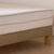 Zoom sur un protège-matelas Bonnuit avec côtés transparents, sommier en lin naturel et pied en bois visible
