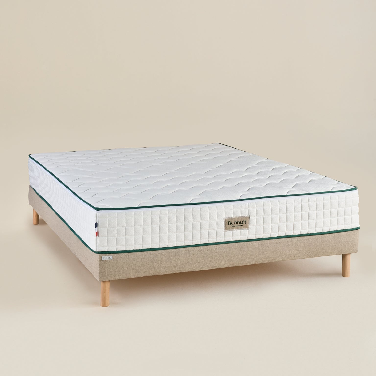 Sommier L’Indispensable avec matelas posé dessus, revêtement en lin naturel et finition soignée