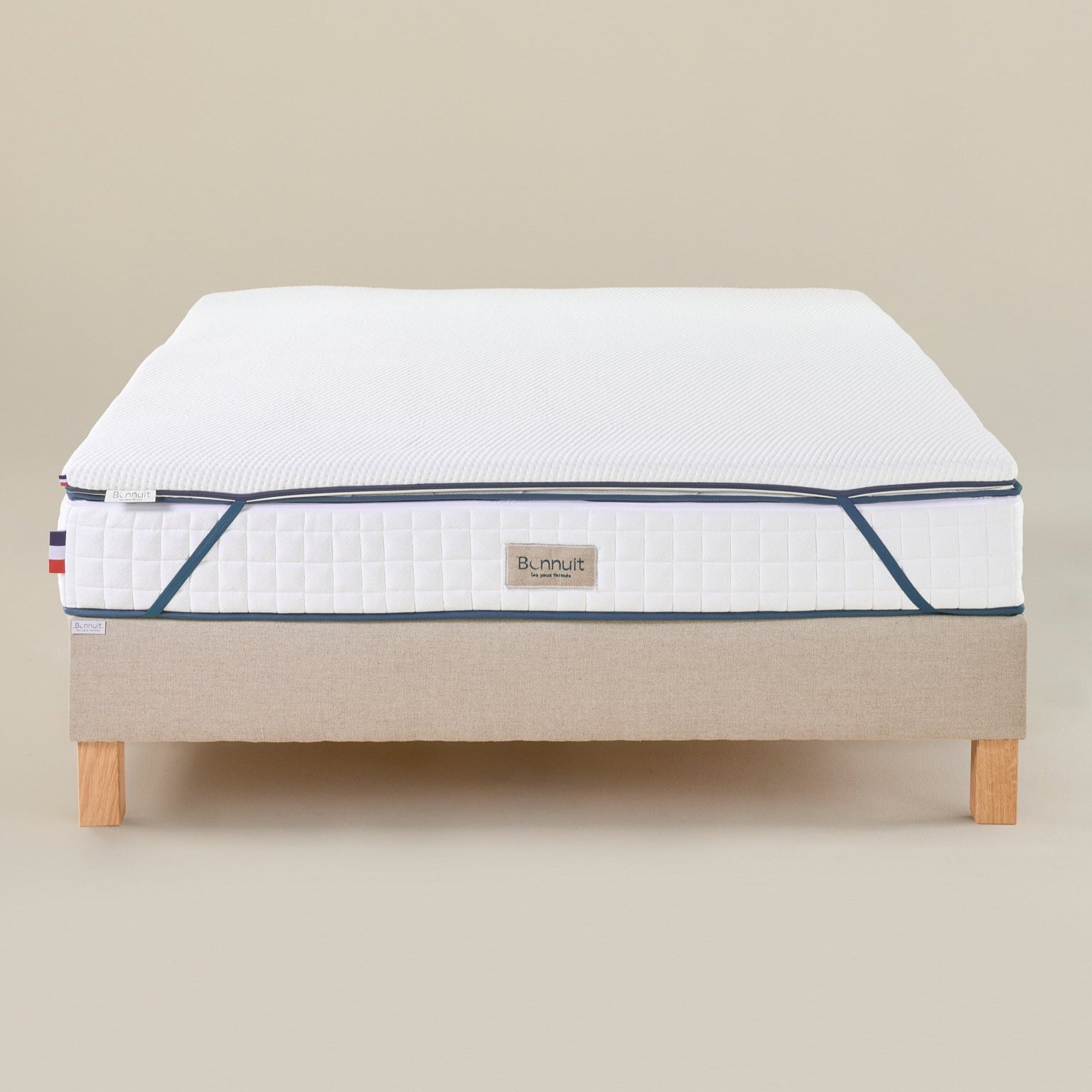 Surmatelas Enveloppant vu de face, élastiques visibles aux quatre coins pour maintien sur le matelas