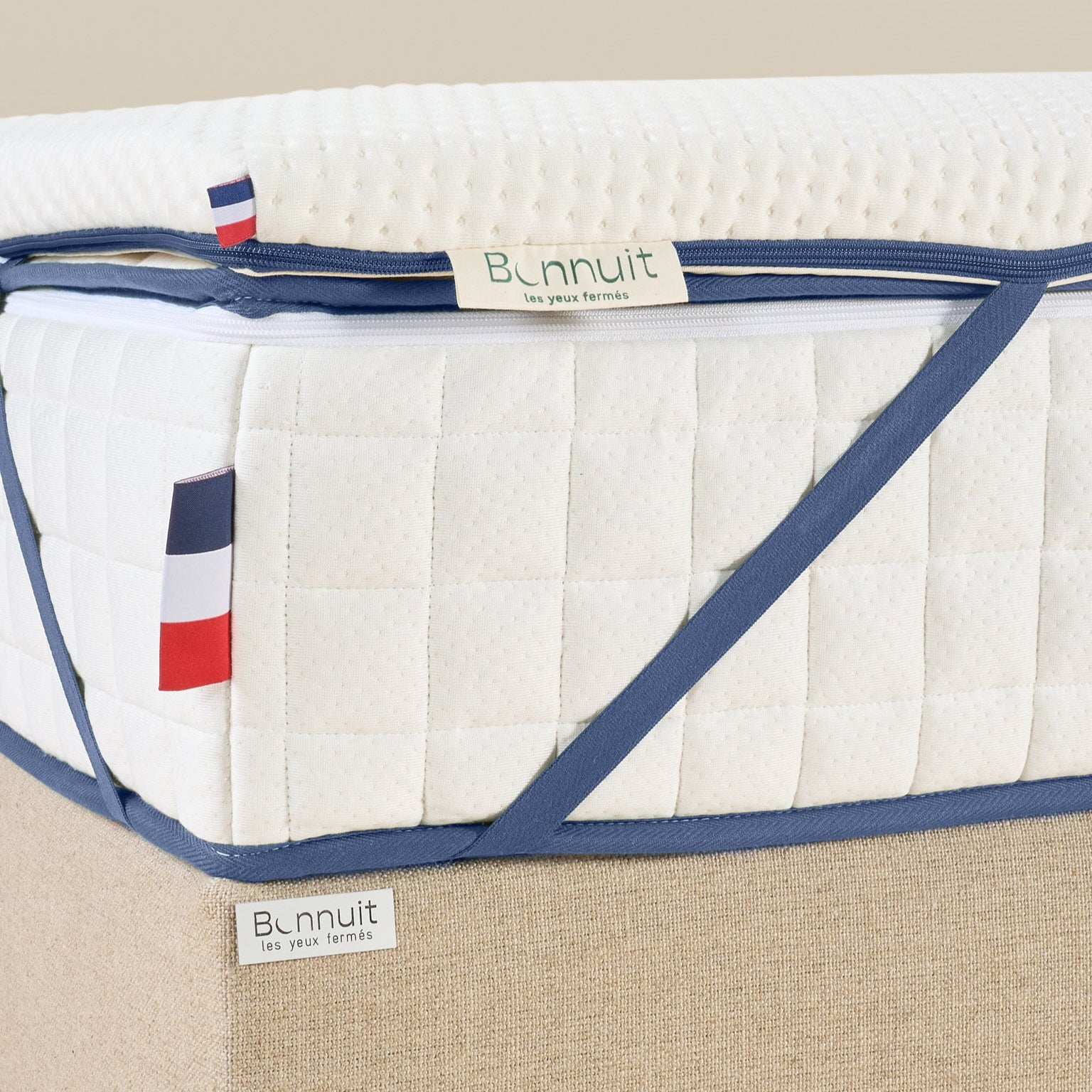Zoom sur un coin du surmatelas Enveloppant avec élastique, drapeau bleu blanc rouge et étiquette Bonnuit