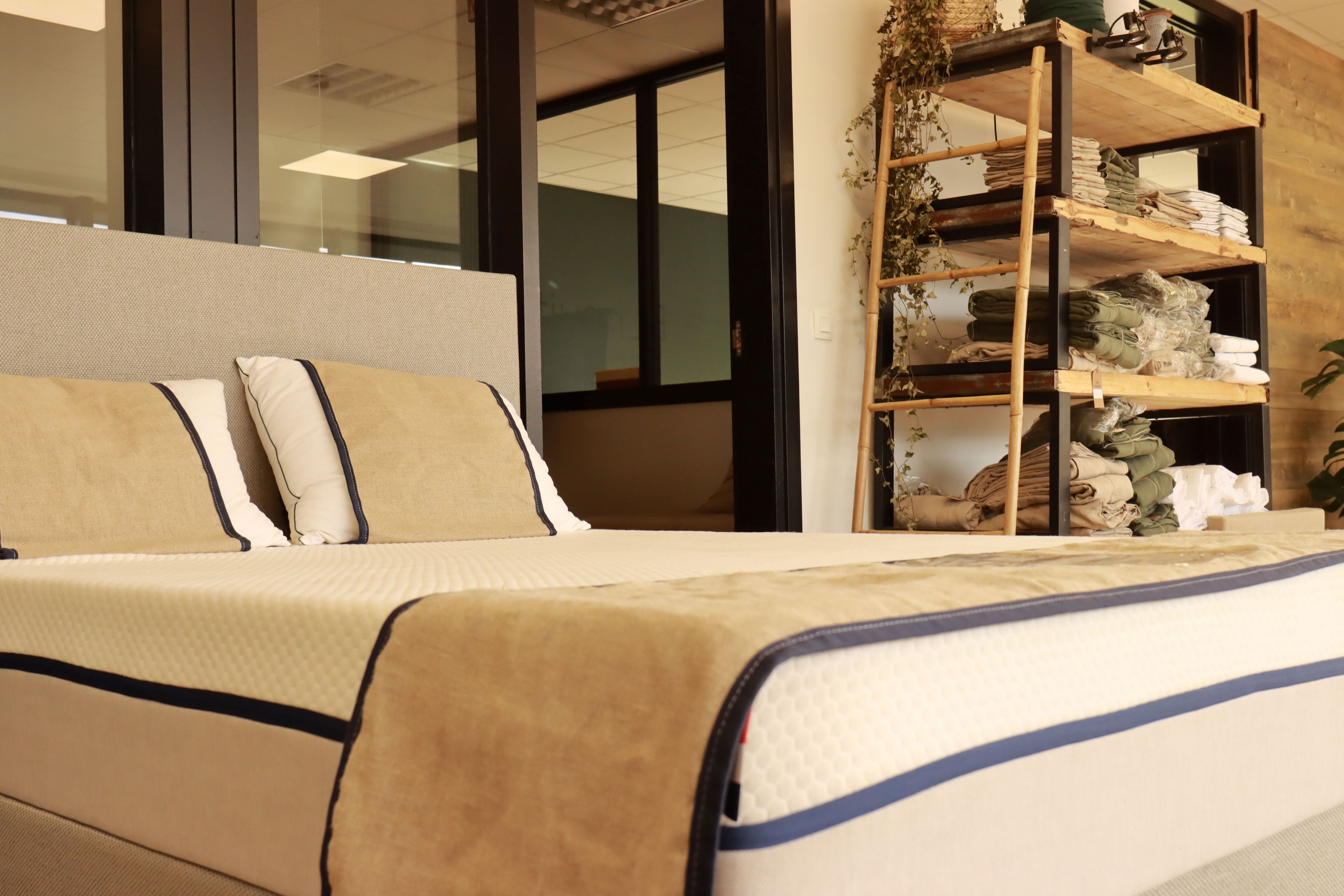 Zoom sur un matelas exposé dans le showroom Bonnuit à Bondues, avec du linge de lit en lin lavé beige et kaki en arrière-plan