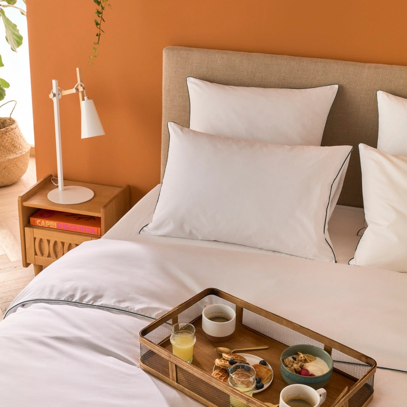 Petit déjeuner posé sur un lit Bonnuit habillé de linge en percale blanche avec liseré vert, ambiance douce