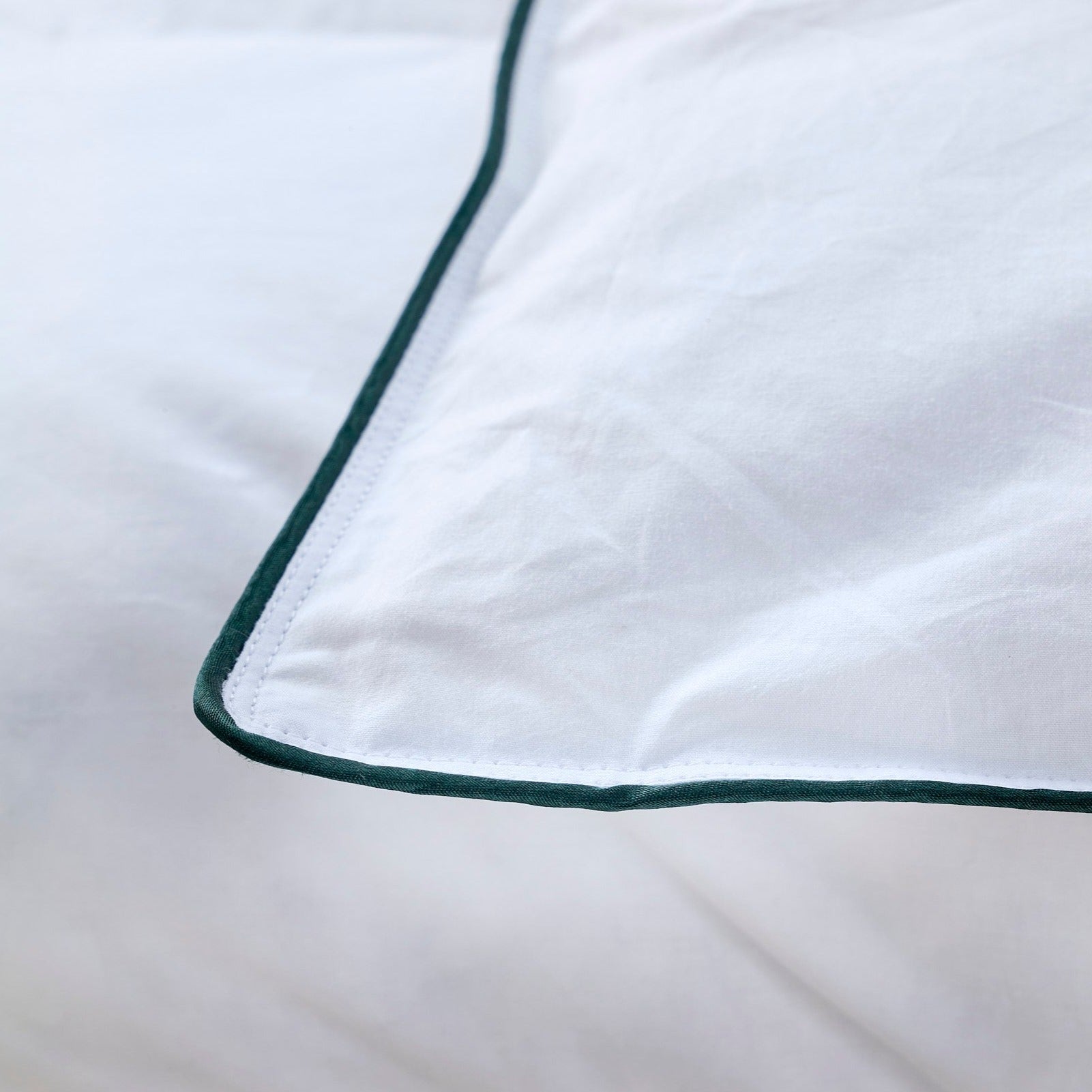 Zoom sur le liseré vert de la taie d’oreiller en percale blanche, finition soignée